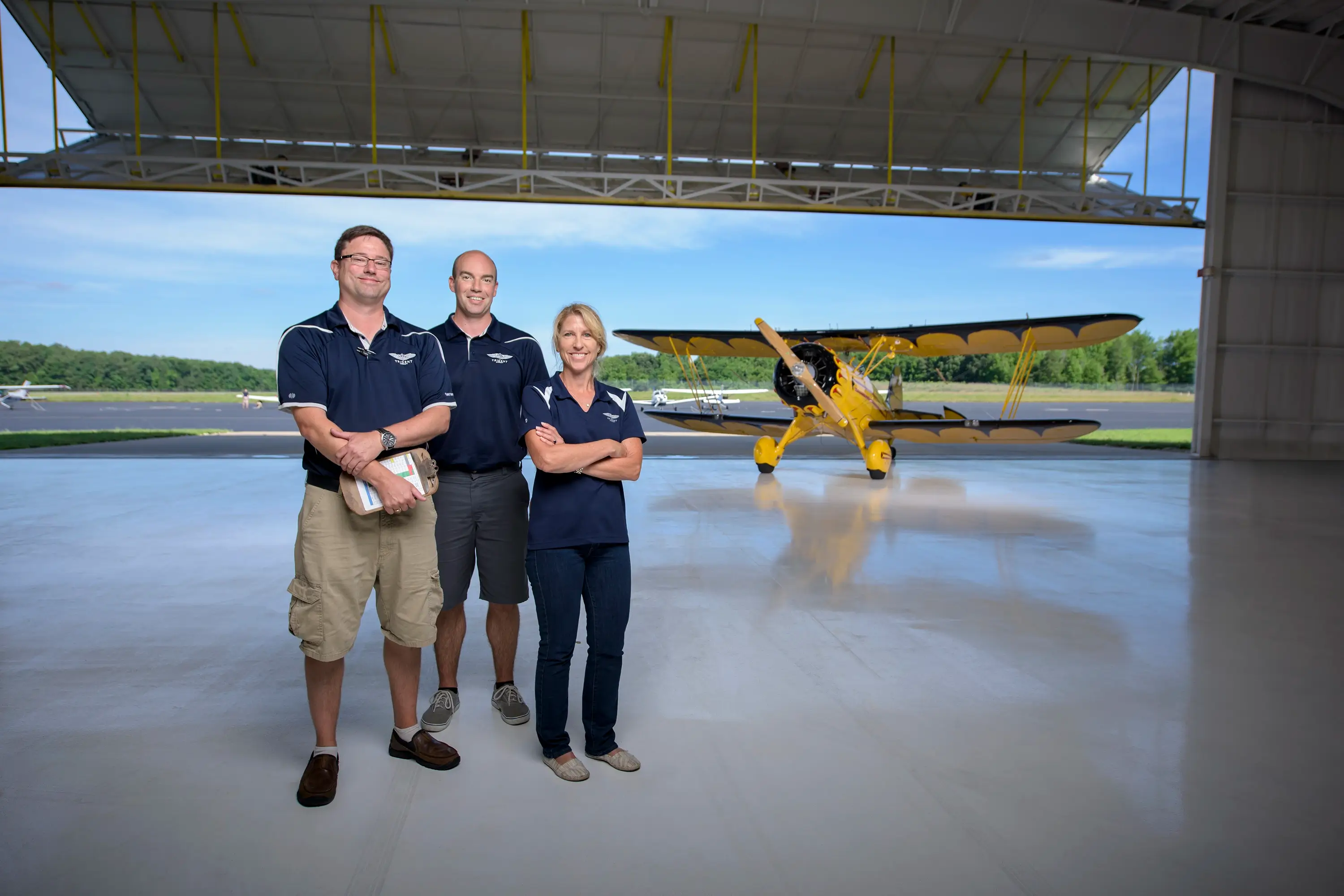 A team standing in an airport hangar in front of a plane