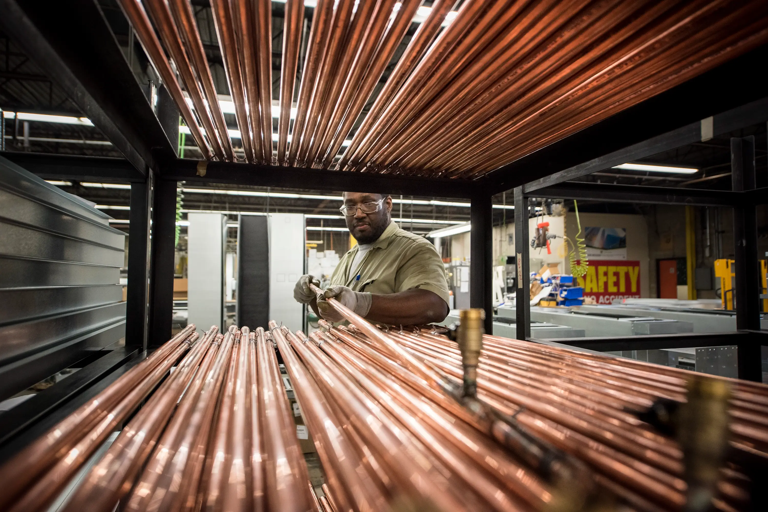 A man placing copper pipes onto a rack